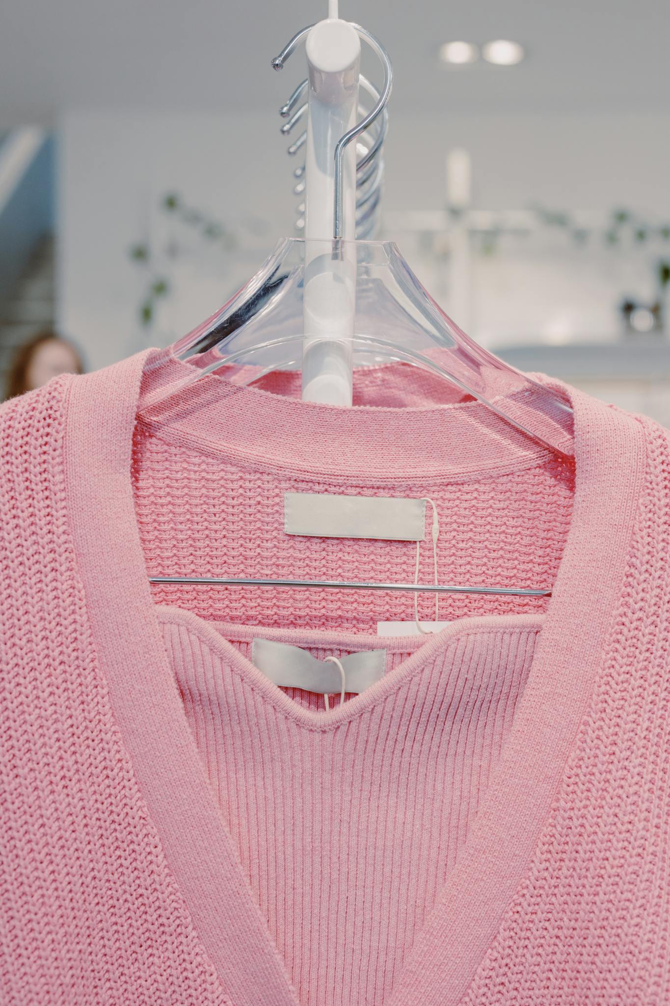 Close-up of a pink knit sweater on a hanger indoors, perfect for fashion and retail themes.